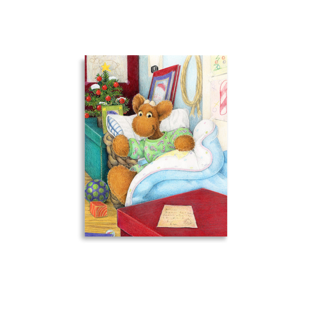 Elliot Moose a children's book character, is jumping out of his basket bed to look at a big red box at the end of his bed. A Christmas tree is in the back ground. From the Book Elliot's Christmas Surprise by Andrea Beck